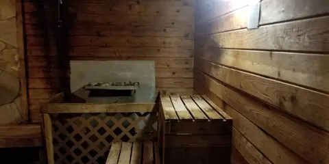 An interior view of a wooden sauna room with benches and a heater.