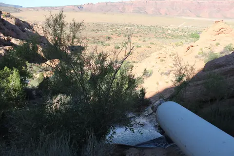 Water flowing from a large pipe into a rocky landscape.
