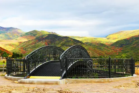 A decorative metal footbridge with mountains in the background.