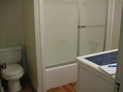 A bathroom showing a toilet, a bathtub with sliding glass doors, and a vanity counter.