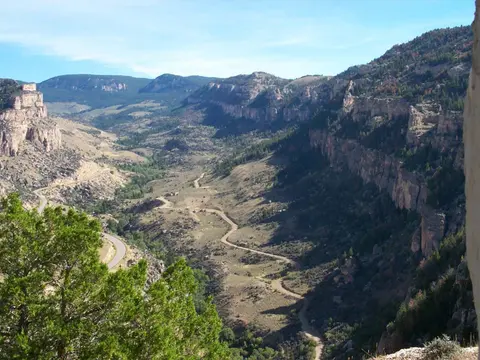 A winding dirt road runs through a deep valley between steep, rocky cliffs.