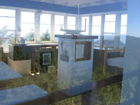 The interior of a fire lookout tower with windows looking out over a forest.
