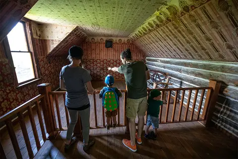 A family looks into an attic room from a wooden loft.