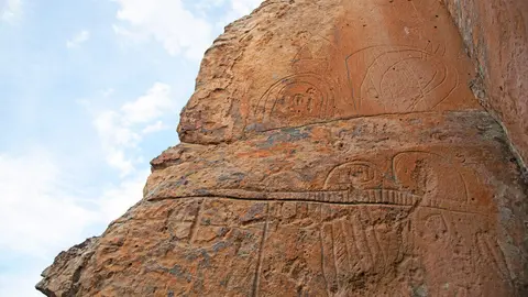 An ancient rock carving or petroglyph on a cliffside.