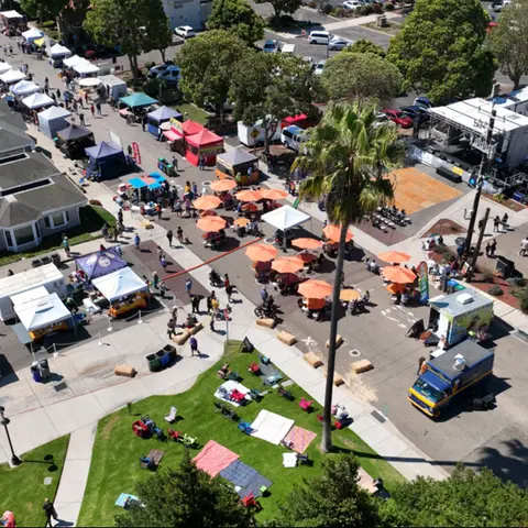 An aerial view of an outdoor festival with tents, food trucks, and attendees.
