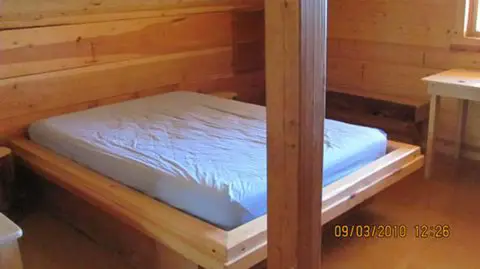 A wooden bed inside a rustic cabin.