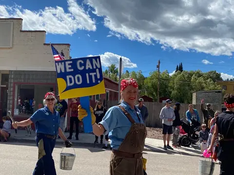 People dressed as Rosie the Riveter march in a street parade.
