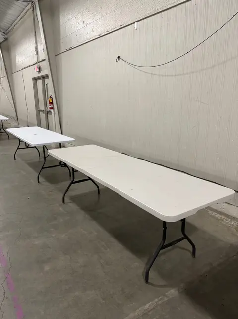 Two folding tables are set up in a large indoor room.