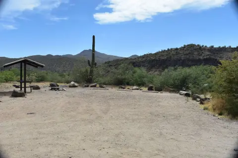 An outdoor picnic area with a covered table and desert landscape in the background.