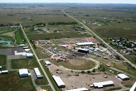 Aerial view of an outdoor arena, fairgrounds, and surrounding rural landscape.
