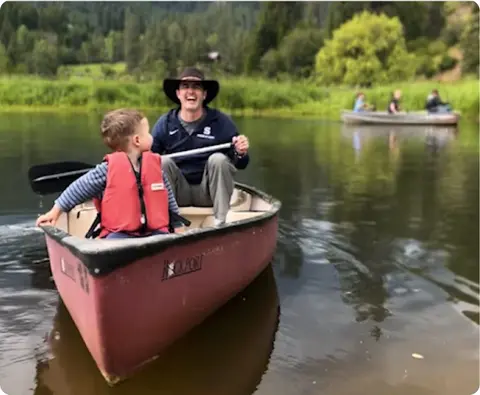 A man and a child in a canoe on a lake.