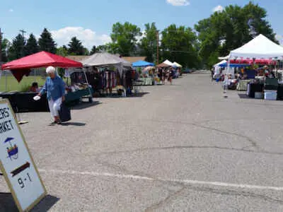An outdoor market with tents and vendors set up in a parking lot.