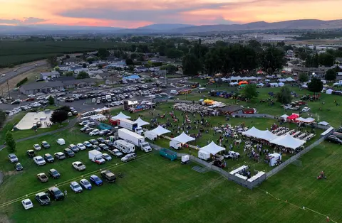 An aerial view of an outdoor gathering in a park at sunset.