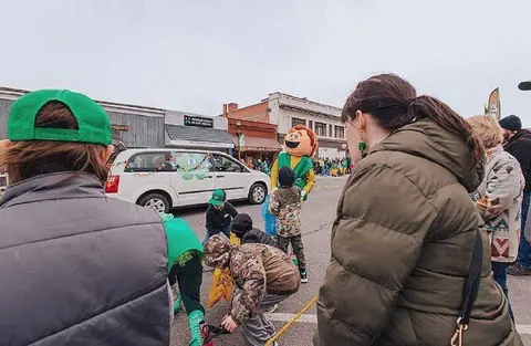 People gather on a street during an outdoor parade event.