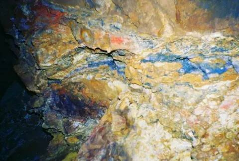A close-up view of a rocky underground formation with colorful mineral deposits.