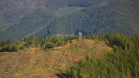A fire lookout tower stands on a forested ridge.