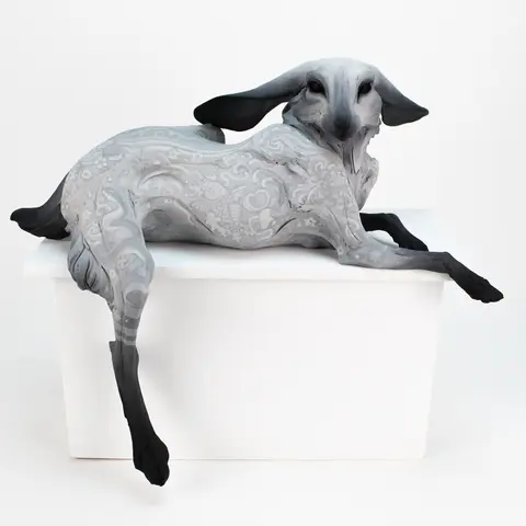 A detailed sculpture of a creature rests on a white pedestal.