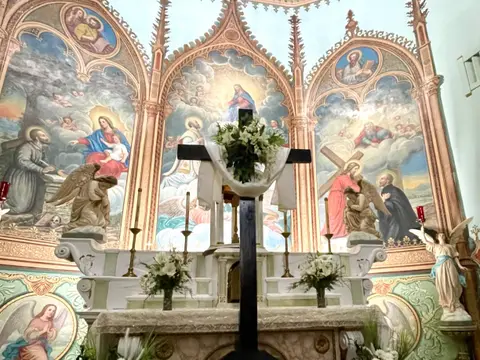 An interior view of a church altar with religious paintings and a cross.