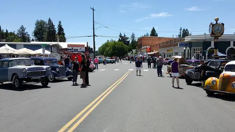 A street lined with classic cars and people walking during an outdoor event.