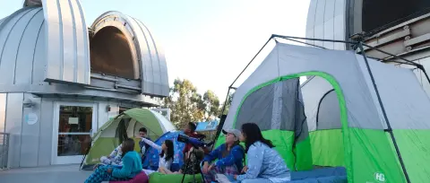 Children camping out in tents near an observatory.