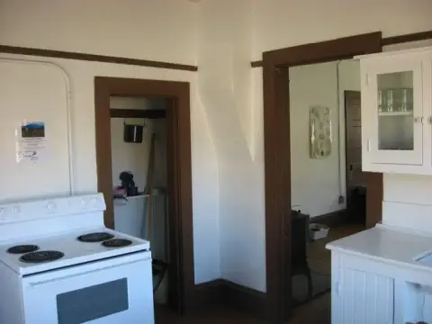 Interior view of a kitchen featuring a white electric stove and brown doorways.