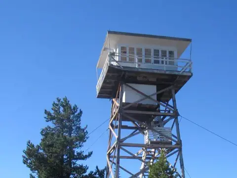 A fire lookout tower stands against a clear blue sky.