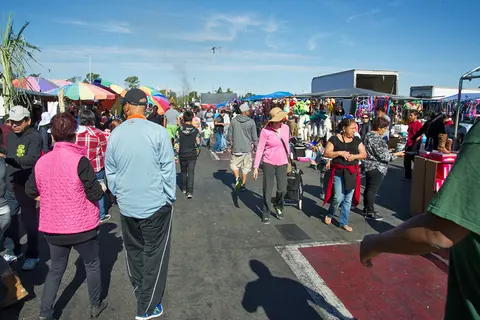 A crowd of people walking through an outdoor market.
