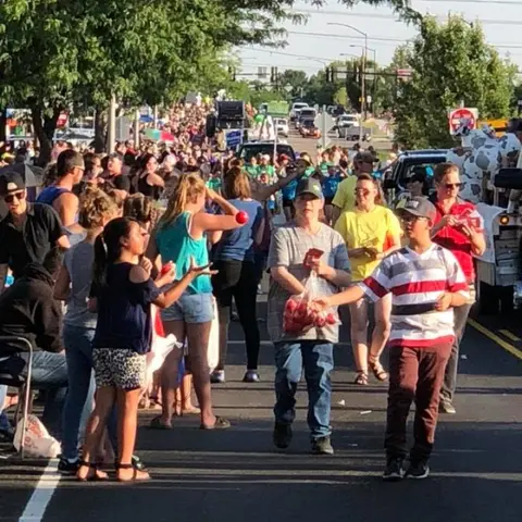 A crowd of people gathers along a street during an outdoor event.