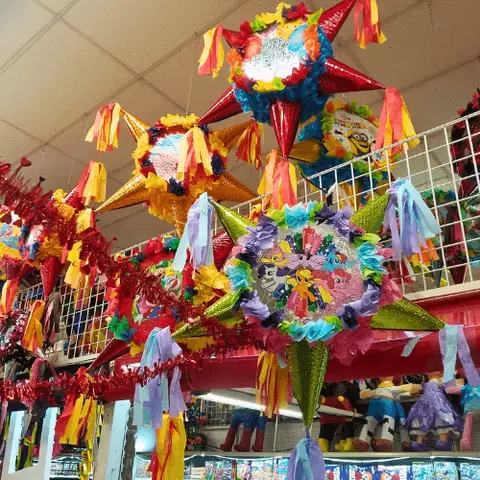 Colorful star-shaped piñatas hang from the ceiling inside a store.