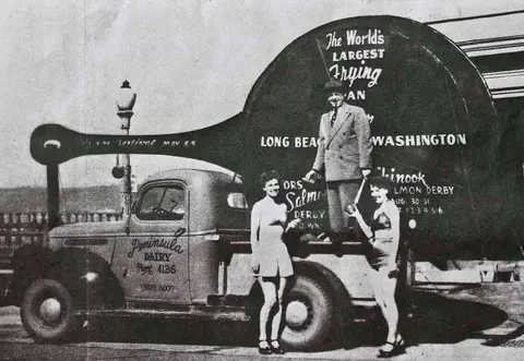 Historic photo of people posing with a giant frying pan on a truck.