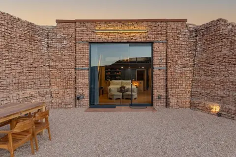 A stone-walled building exterior with a large glass door opening to an interior room.