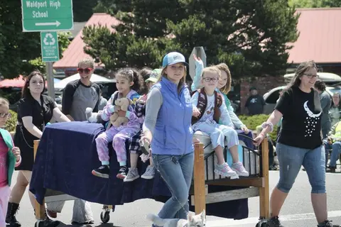 A group of people and children participating in a parade outdoors.