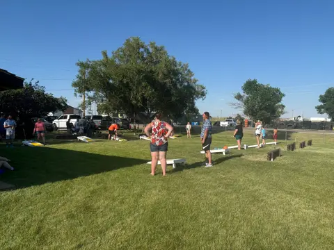 People playing cornhole outdoors on a sunny day.