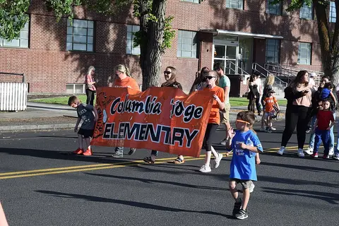 A group of people carrying a banner on a street in front of a brick building.