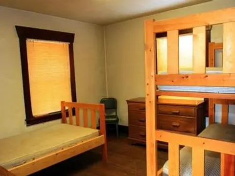 Interior view of a rustic bedroom with bunk beds and a single bed.