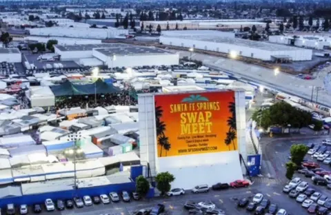 An aerial view of a large market with a prominent sign and parking lots.