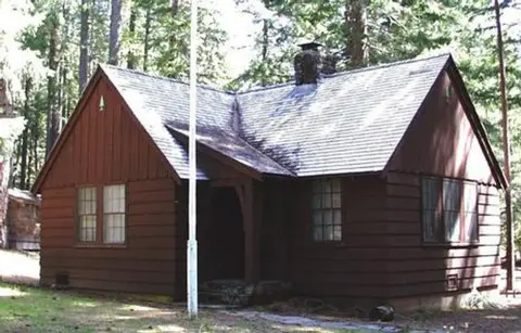 A brown wooden cabin exterior surrounded by trees.