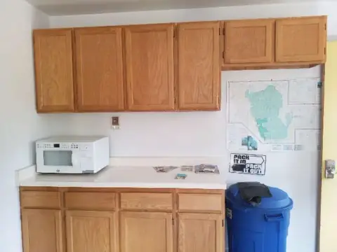 A kitchen interior featuring wooden cabinets and a white countertop with a microwave.