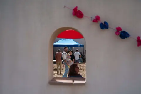 People walking through an outdoor event viewed through an arched window.