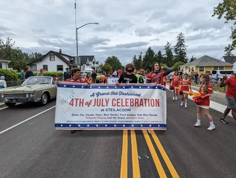 People carry a celebration banner down a street during a parade.