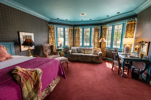 An interior shot of a bedroom with plaid walls and a blue ceiling.