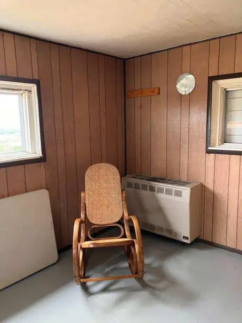 A wooden rocking chair sits in the corner of a room with wood paneling.