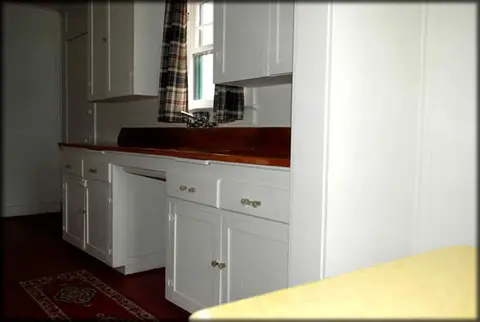 A view of a traditional kitchen interior with white cabinets and a wooden countertop.