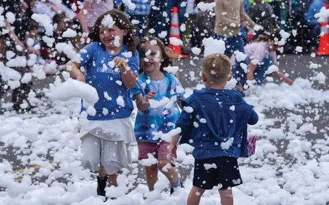 Children play in a foam party outdoors.