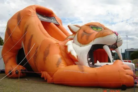 A large inflatable tiger slide outdoors.