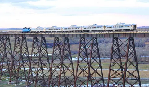 A train crossing a tall trestle bridge over a valley.