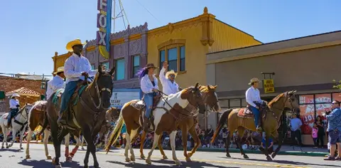 People ride horses down a street in a parade.