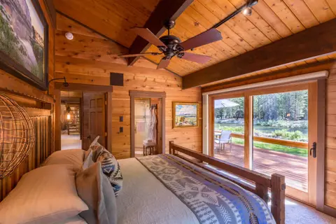 A rustic wooden bedroom with a view of a river outside.
