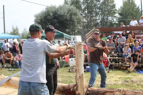 Men compete in a log sawing event in front of a crowd.