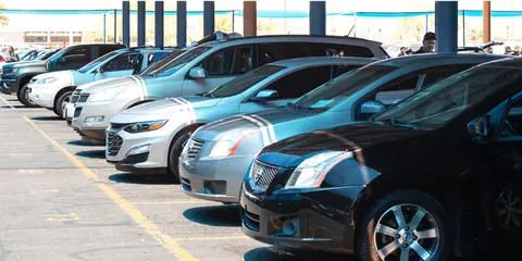 A row of cars parked under a shaded parking structure.